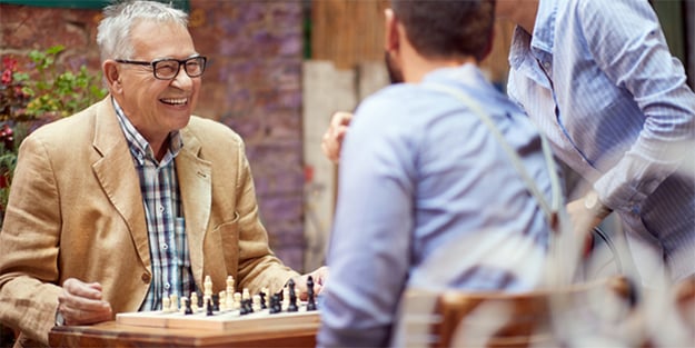 Older man playing chess outdoors