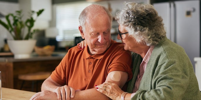 Senior couple embracing while sitting at a table.